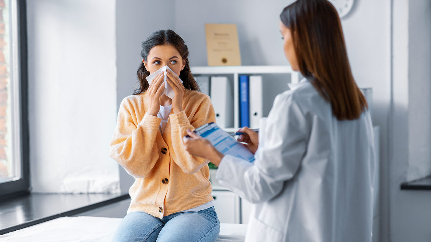 Ženska z gripo na pregledu pri zdravnici.