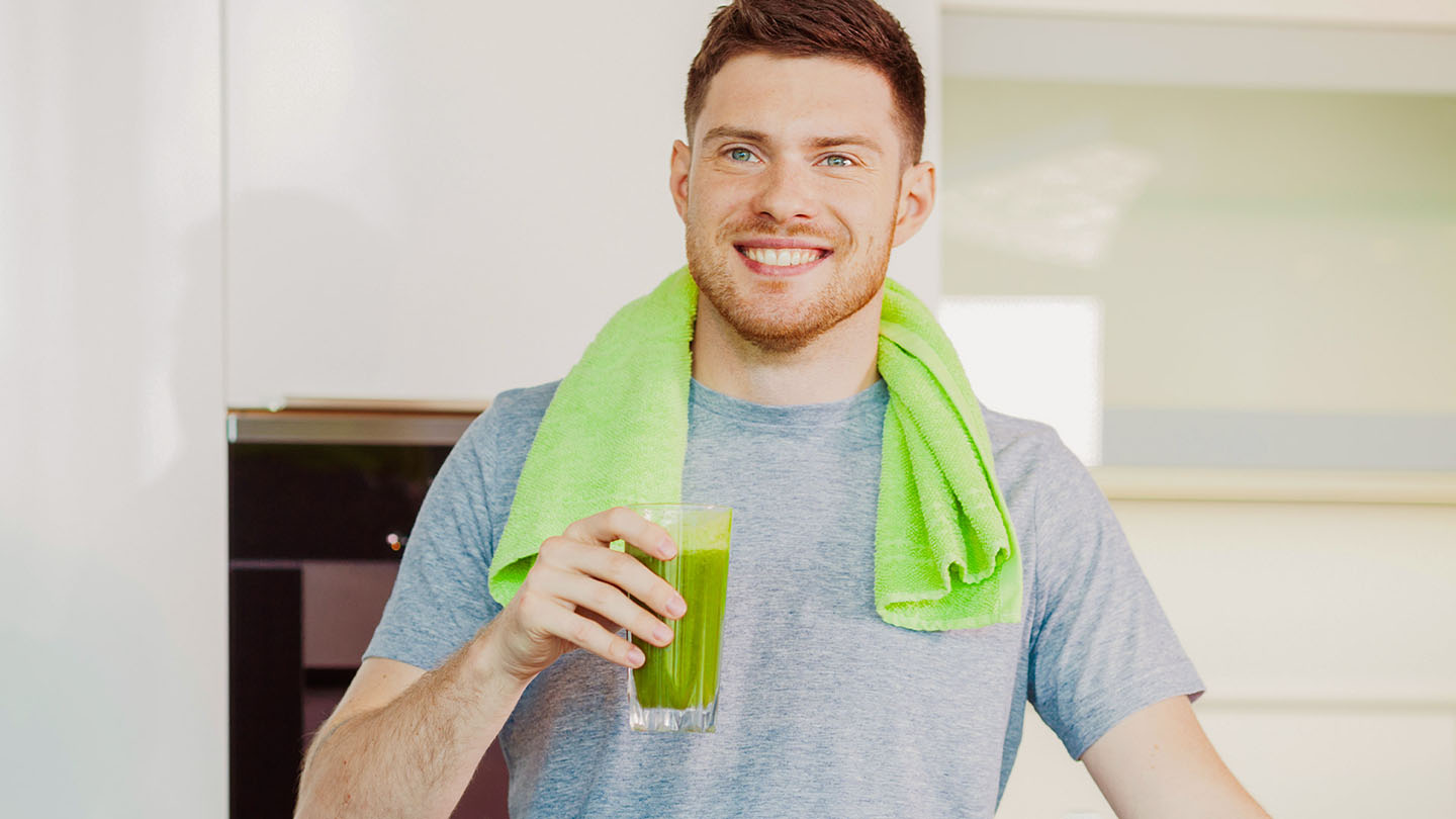 Moški uživa zdrav zelen smoothie.