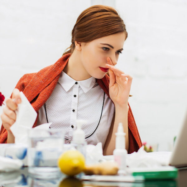 Prehlajena bolna ženska v pisarni.