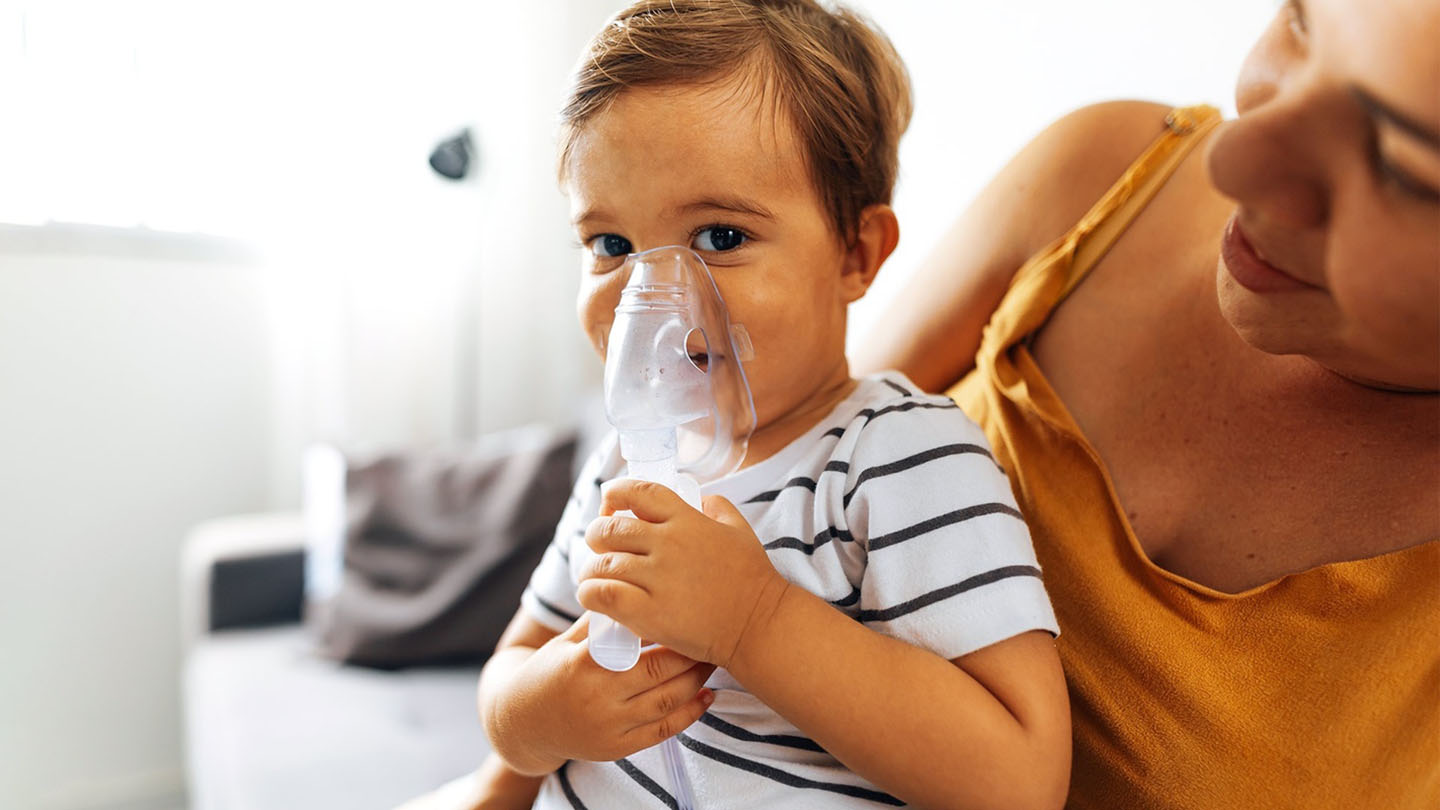 Otrok z dihalno masko in njegova mati.