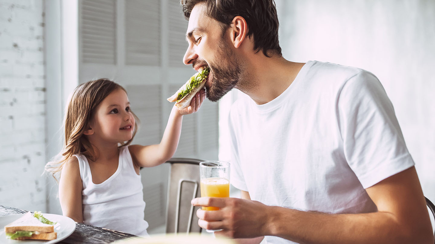 Oče in otrok uživata v sendviču.