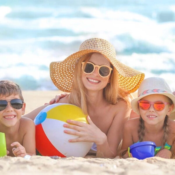 Poletje in bolezni pri otrocih; družina na morju uživa na plaži in soncu.