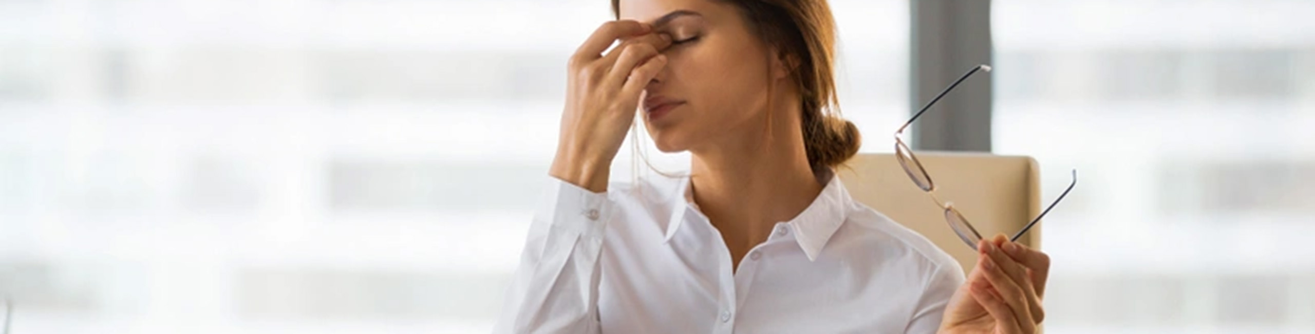 Utrujena ženska za mizo v pisarni, stres, izčrpanost.