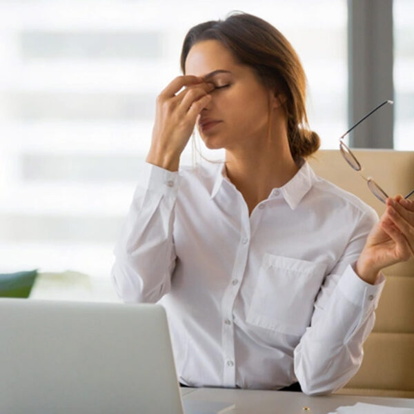 Utrujena ženska za mizo v pisarni, stres, izčrpanost.