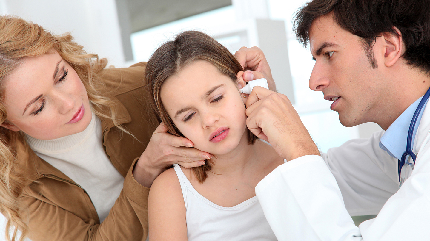 Zdravnik preglejuje uho deklice, vnetje ušes.